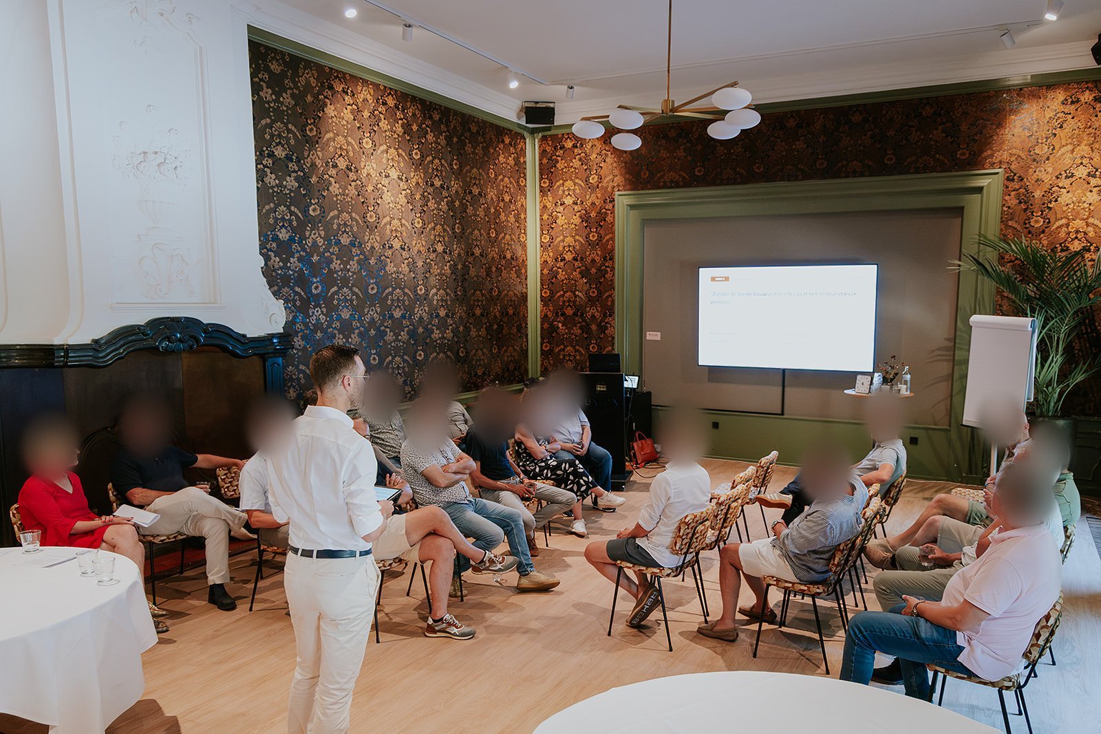 Een debat tijdens een plansessie: de zaal zit in twee groepen tegenover elkaar, de stelling staat op het scherm